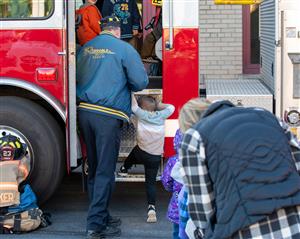 A student being helped into a firetruck by a firefighter.